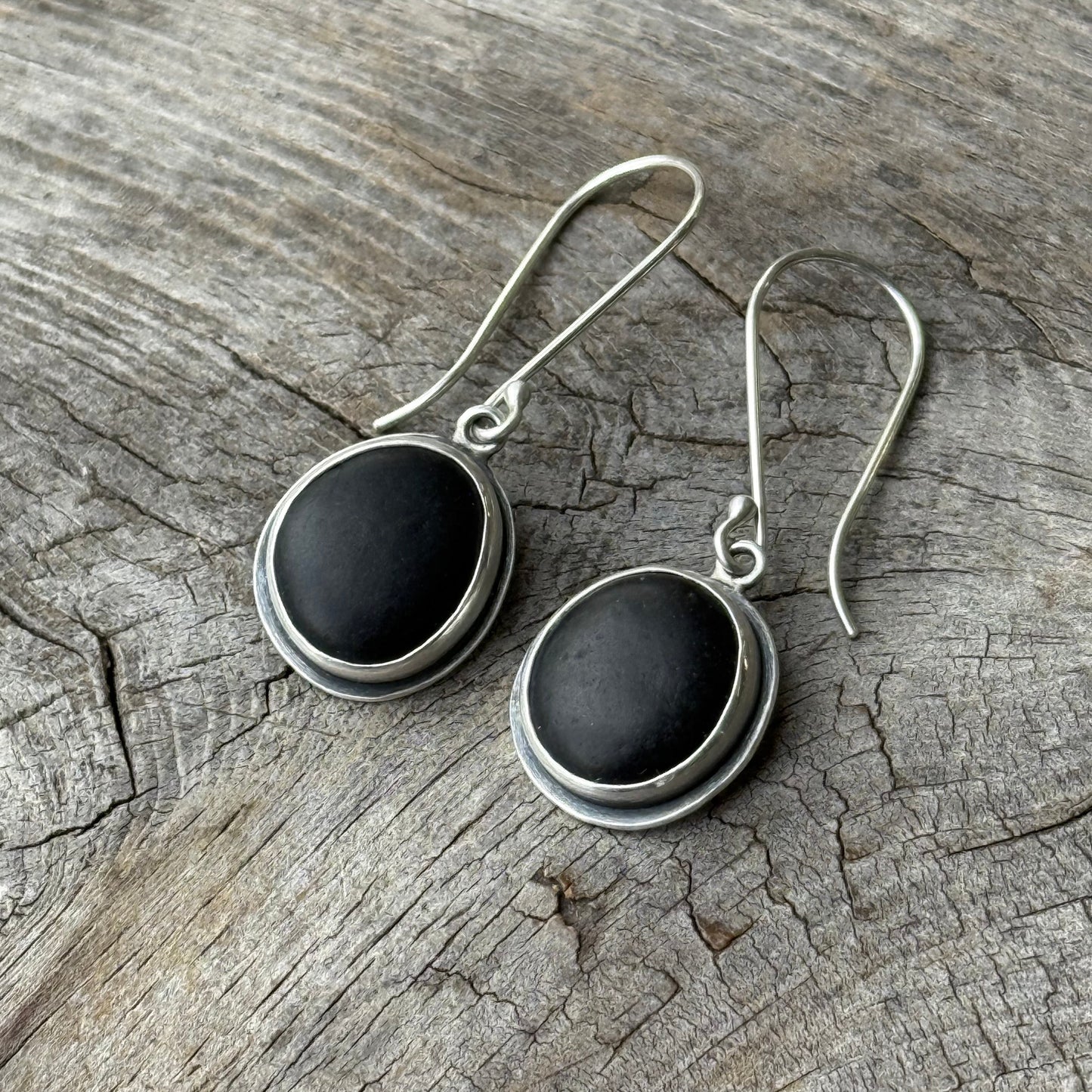 Silver earrings with black stones on a wooden surface