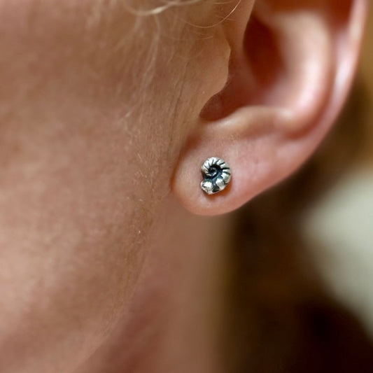 Close-up of an ear wearing a fiddlehead fern silver stud earring.